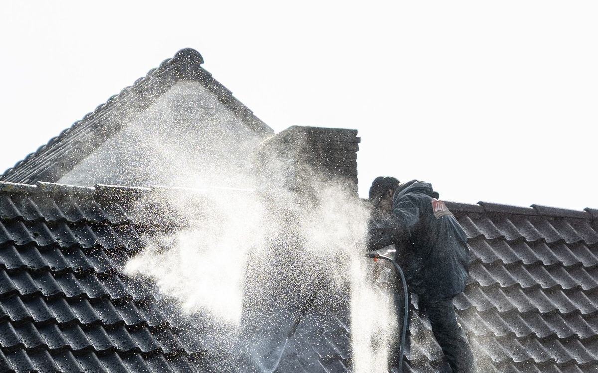 Operative pressure washing moss from a tiled roof